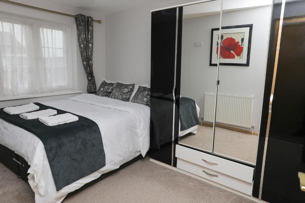 a bedroom with a large bed and a mirror at Entire 3 bedroom house, 3 toilets, 2 baths, sleep 9 with free parking in Thamesmead