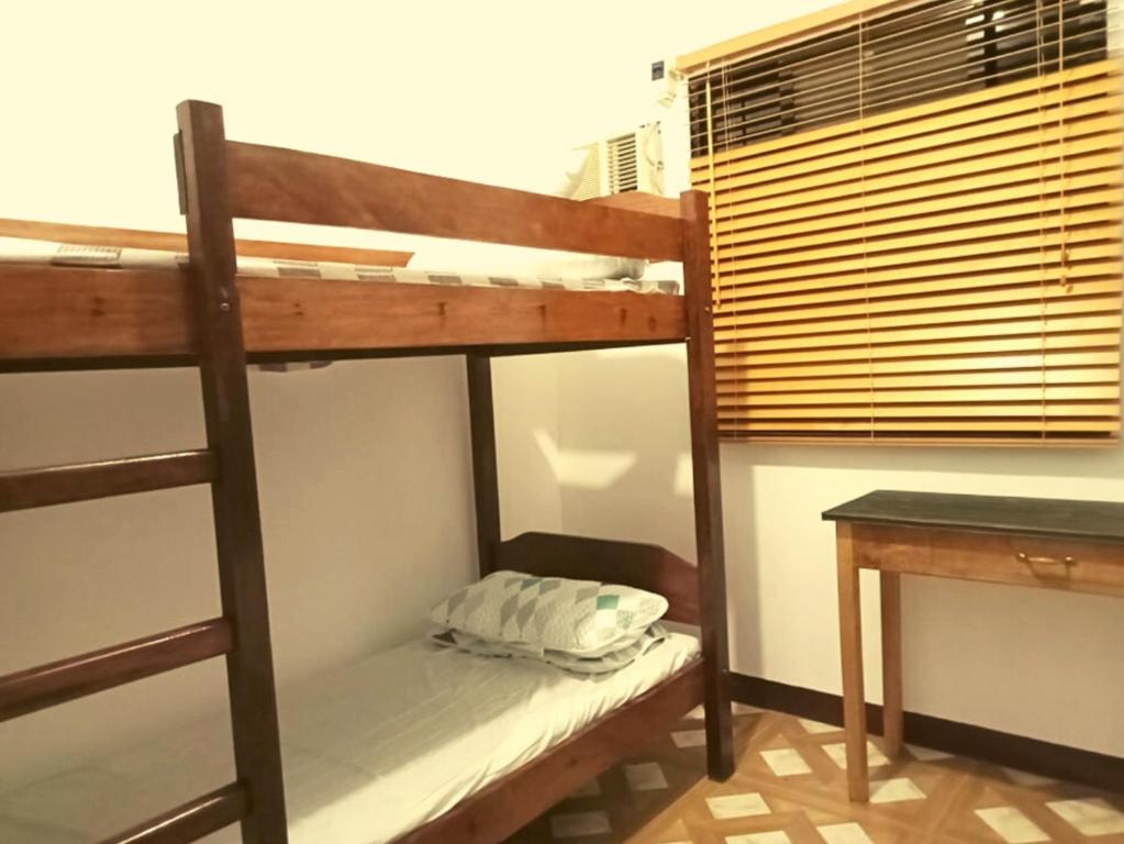 a bunk bed in a room with a desk and a bunk bedutenewayangering at Dos Casa Guest House in Puerto Princesa City