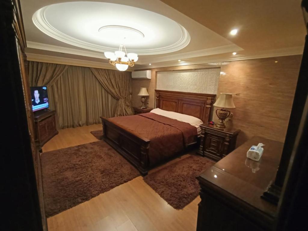 een slaapkamer met een bed en een kroonluchter bij Luxury Apartment In Massaken Sheraton near Cairo Int'l Airport in Caïro