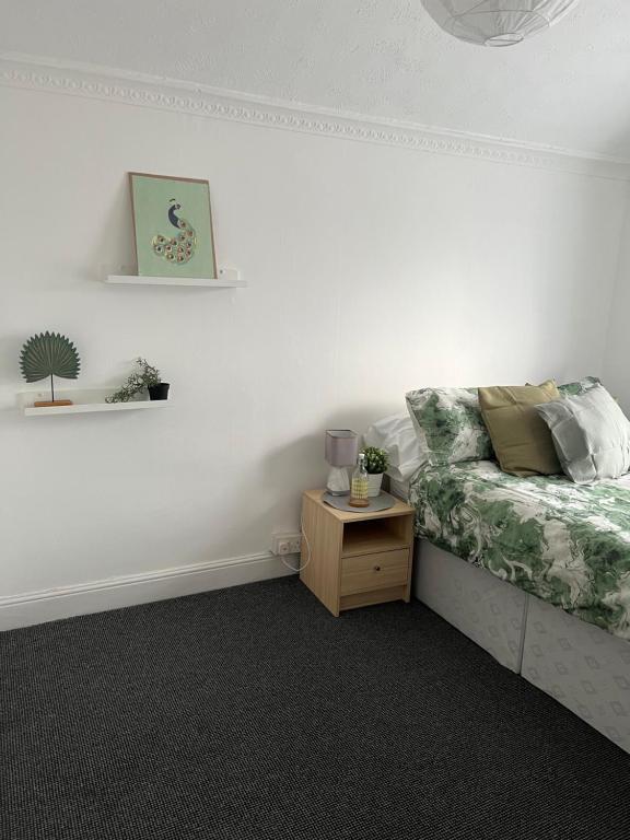 a bedroom with a bed and a nightstand with a table at Spacious family home in Cardiff