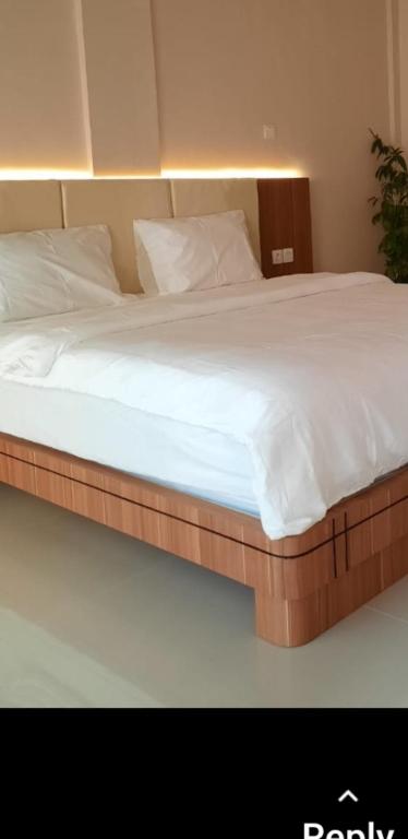 a large bed with white sheets and pillows at Yulides home gardens in Cindakir
