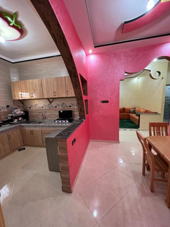 a kitchen with pink walls and a table and a dining room at House tour dakhla in Dakhla