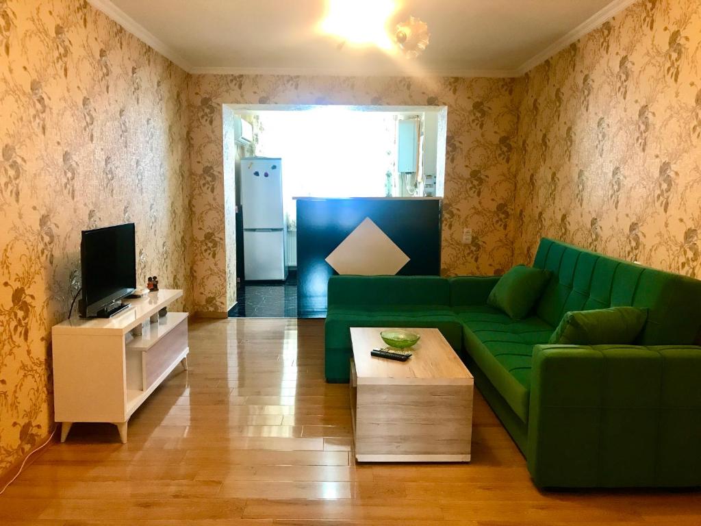 ein Wohnzimmer mit einem grünen Sofa und einem Kühlschrank in der Unterkunft Homee in Tbilisi City