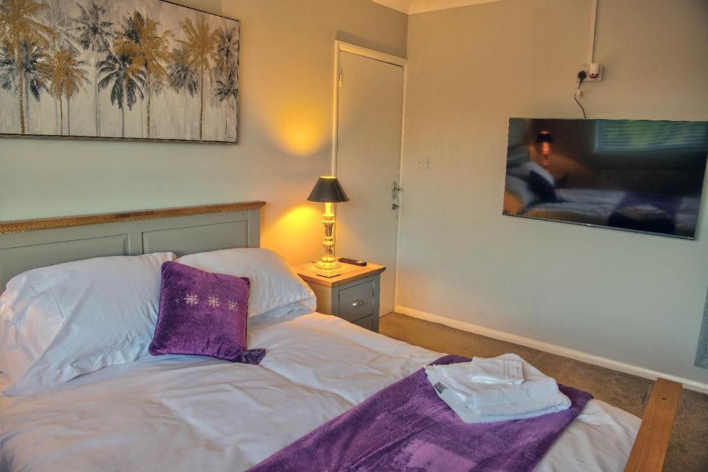 Un dormitorio con una cama con una manta morada. en Oakland en Kettering
