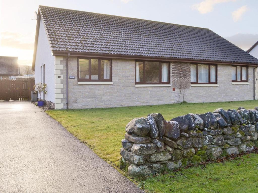 a stone wall in front of a house at Coiltie Cottage in Drumnadrochit