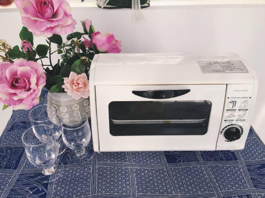 a toaster oven on a table with glasses and flowers at Osaka Glitter 3 floor whole house 6-10 ppl 5mins walk to station in Osaka