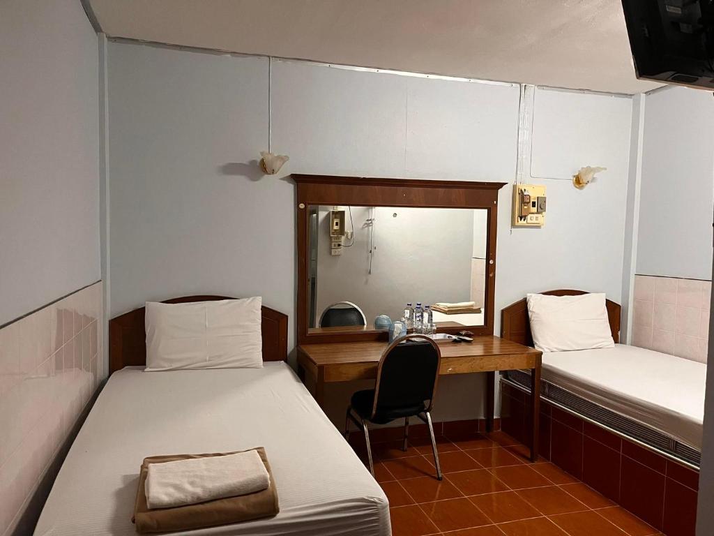 沙敦的住宿－Metro Palace，客房设有两张床、一张桌子和一面镜子。