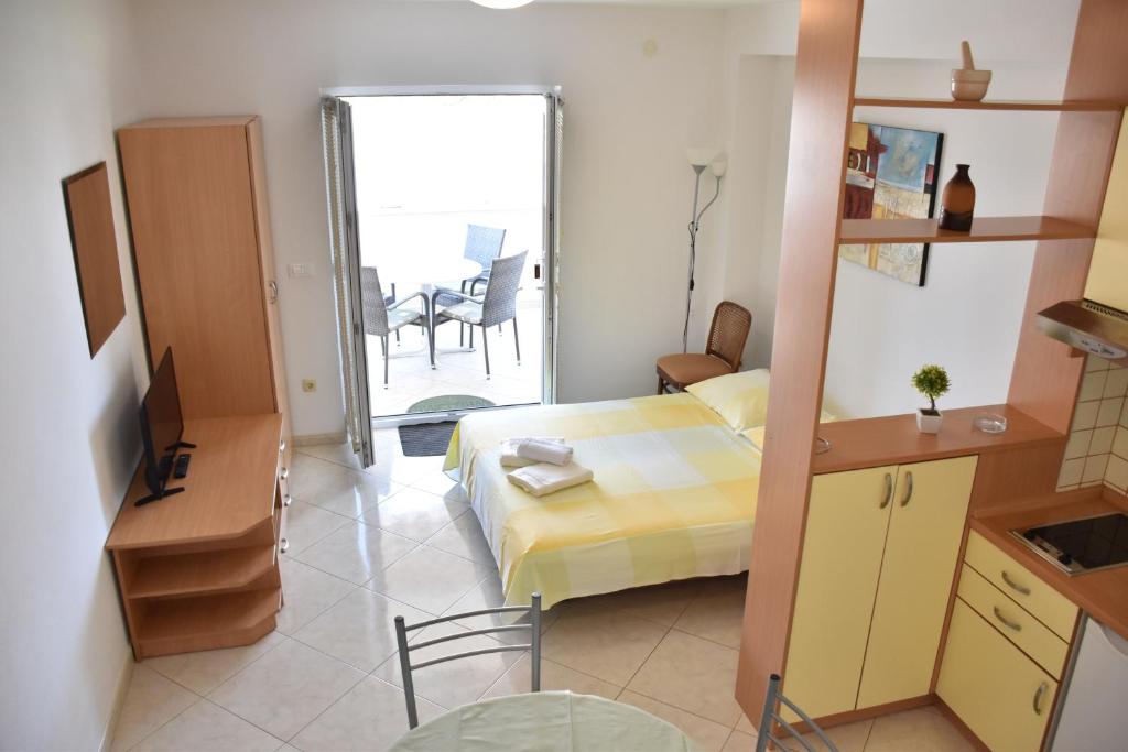 a bedroom with a bed and a balcony with a table at Apartments Stone Tučepi in Tučepi