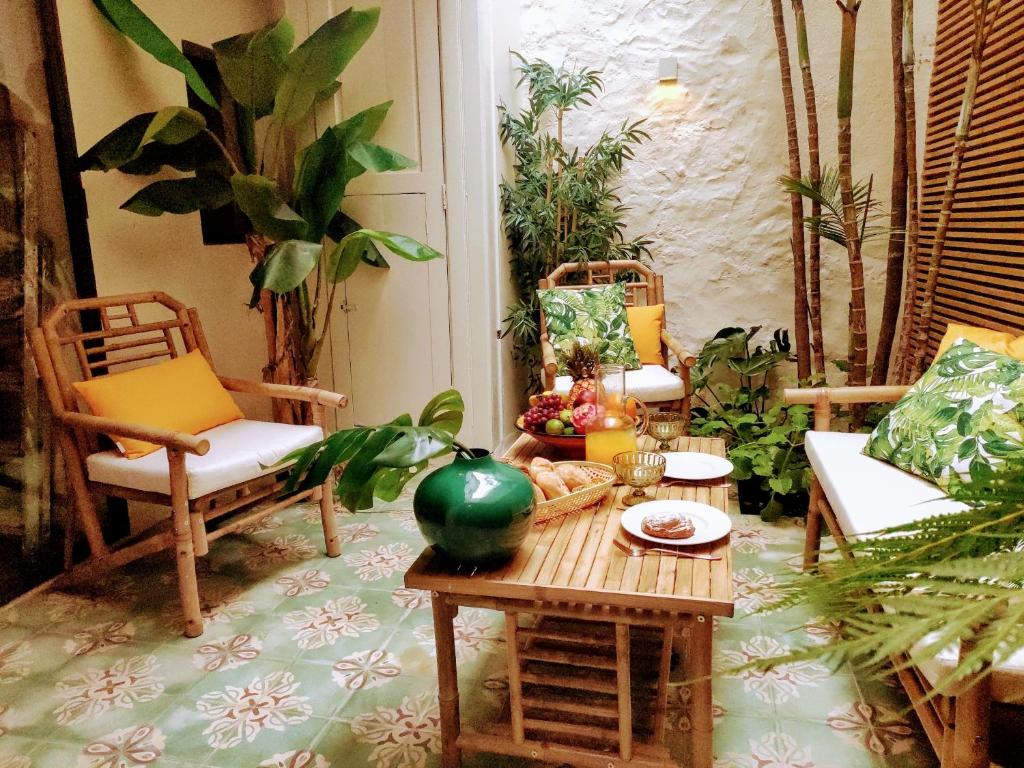 a living room with a table and chairs and plants at Romantic patio-house for 2 in the old centre in La Orotava
