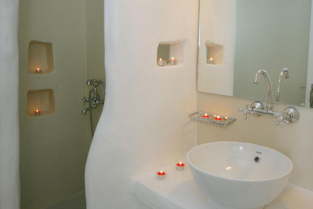 Baño blanco con lavabo y espejo en NINEMIA CALM AND SPA, en Kionia