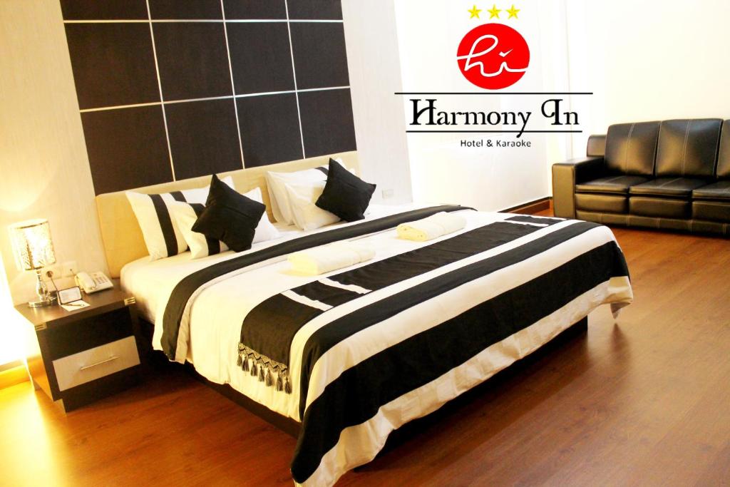 a bedroom with a bed with a black and white blanket at Hotel Harmony In & Karaoke in Pontianak