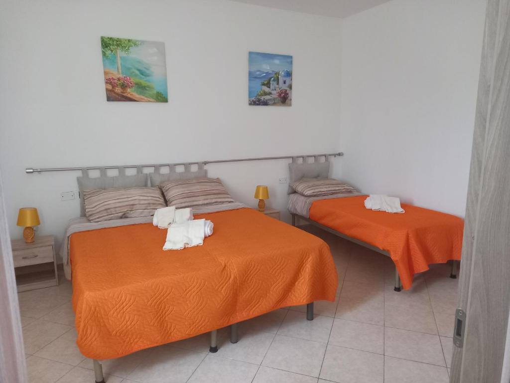 - 2 lits dans une chambre avec des draps orange dans l'établissement B&B PLANET, à Roccella