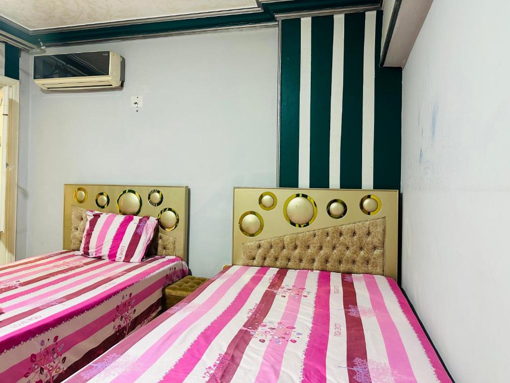duas camas num quarto com riscas cor-de-rosa e brancas em 84 شارع الجليل جسر السويس no Cairo