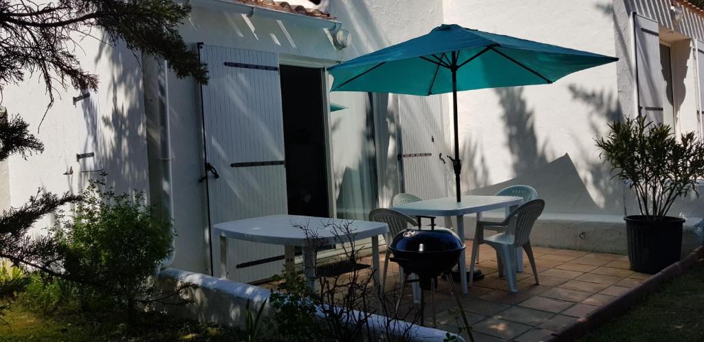 a patio with two tables and an umbrella at Détente à la mer in La Guérinière