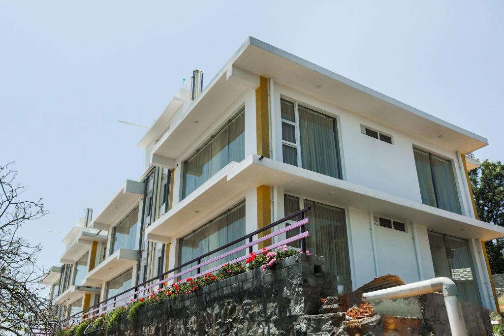 a white building with flowers in front of it at Belair Resorts in Kotagiri