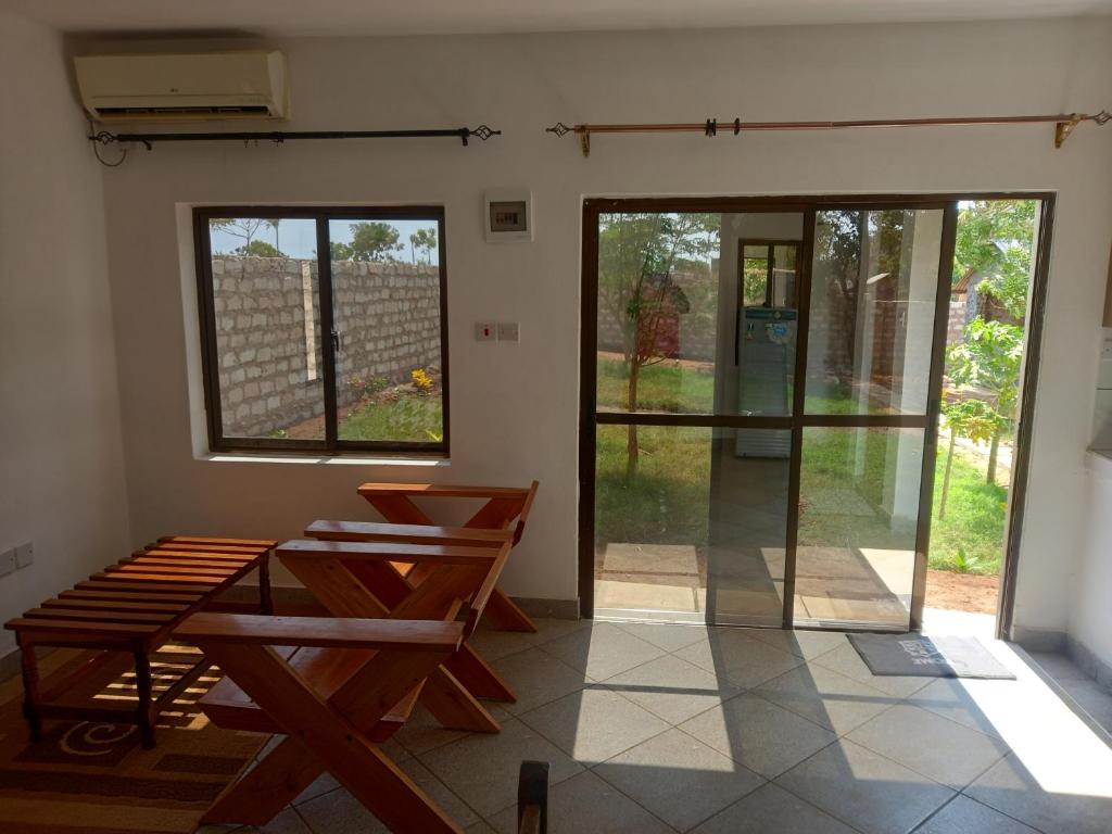 een kamer met een tafel, banken en ramen bij BreezHub Residence in Kikambala
