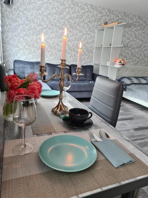 una mesa de comedor con dos platos y velas. en Crystal Apartment, en Gulbene