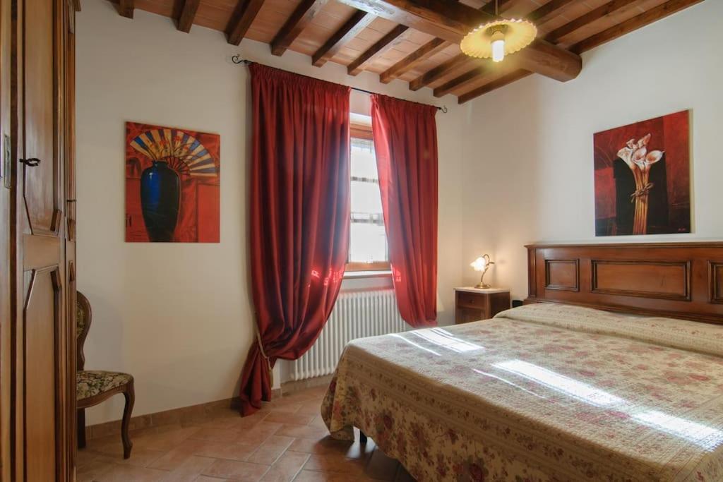 a bedroom with a bed and a window with red curtains at Villa Perugini in Tuoro sul Trasimeno