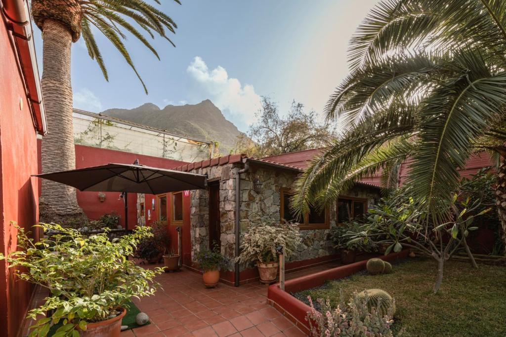 ein Haus mit einem Innenhof mit einem Sonnenschirm in der Unterkunft Papaya Cottage Punta del Hidalgo in Punta del Hidalgo