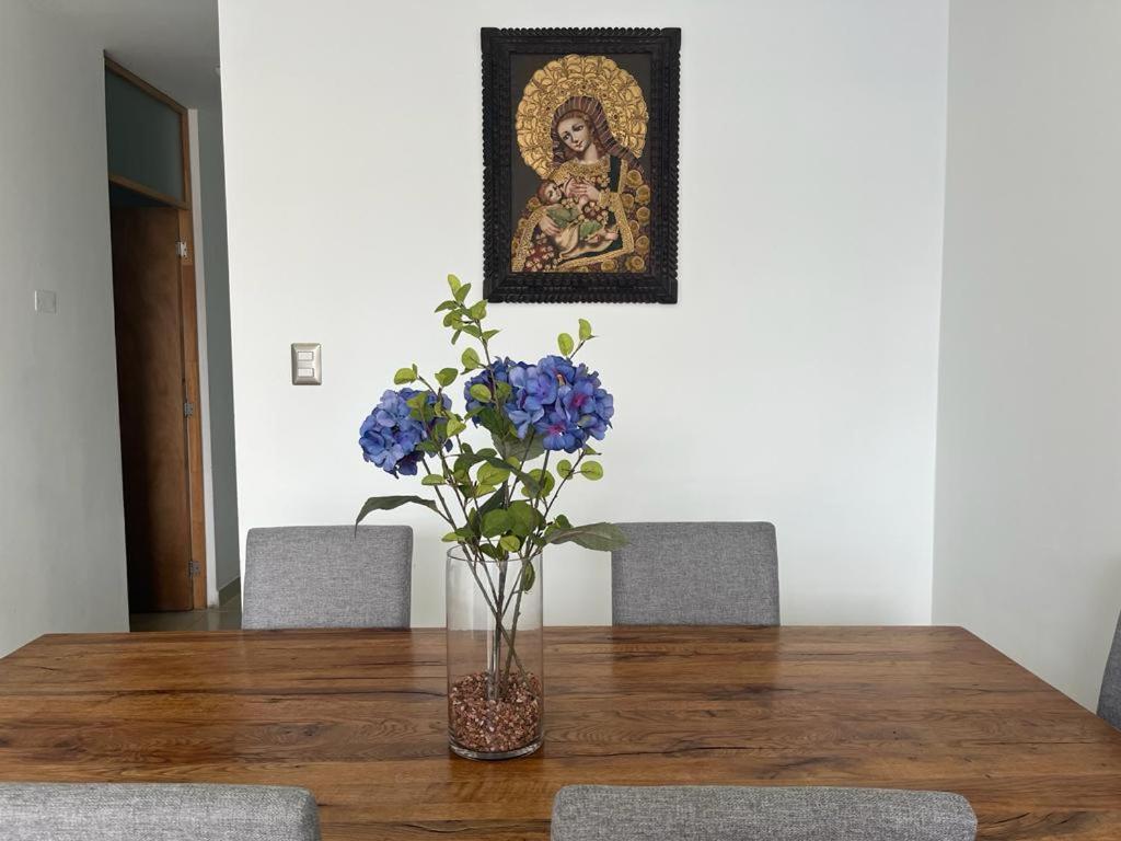 un jarrón de flores azules sentado en una mesa de madera en Ica tierra del sol eterno 2, en Ica