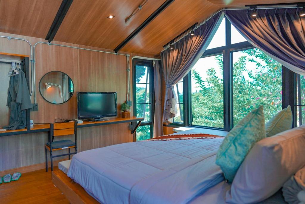 a bedroom with a large bed and a television at Heaven Hill Camping in Ban Thung Na