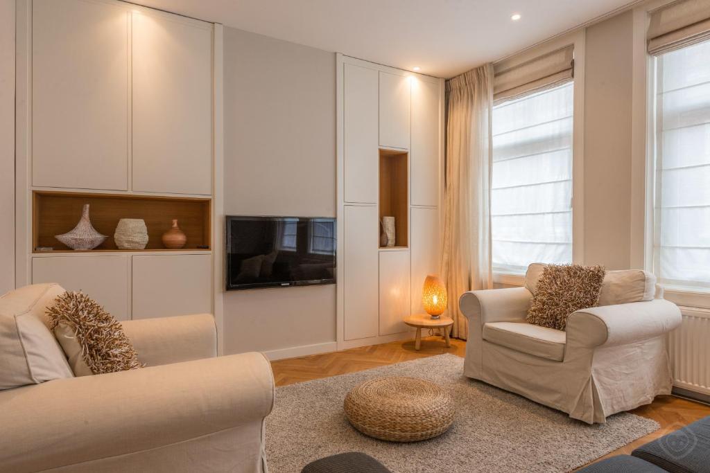 uma sala de estar com duas cadeiras e uma televisão em Old City Centre apartments - Nieuwmarkt area em Amsterdã