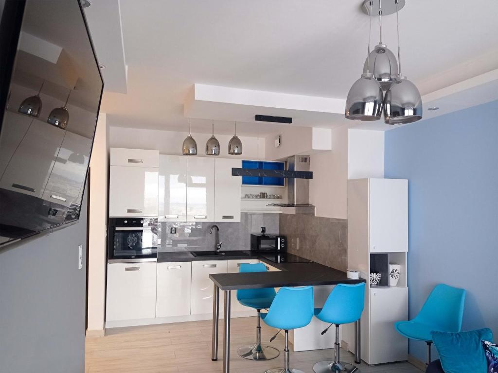 a kitchen with a table and blue chairs at Apartament z widokiem na panoramę Gdyni w Modern Tower ATAL in Gdynia