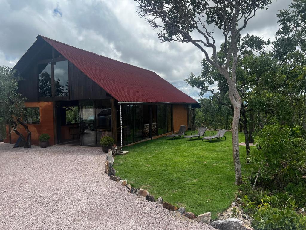 uma casa com um telhado vermelho e um jardim de relva em Rancho Aroeira em São Jorge