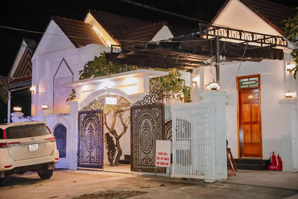 a white house with a gate and a car parked in front at Lavender Tan Thanh Hotel mini resort in Cong Thanh (3)