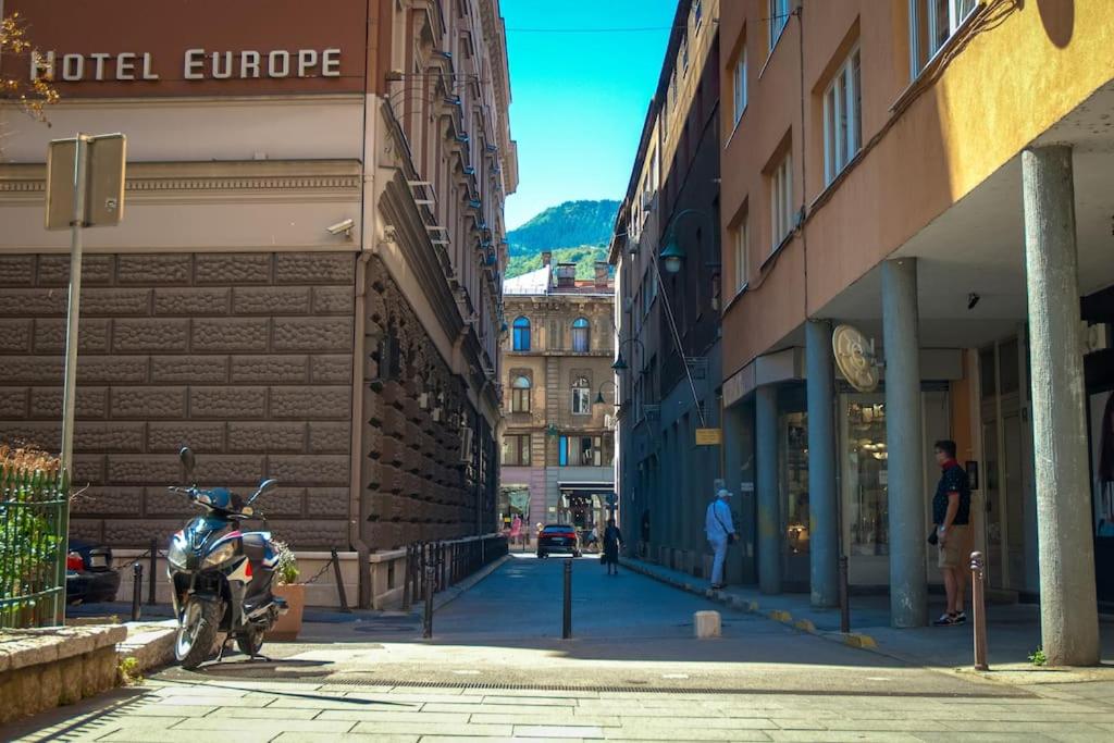 ein Motorrad, das auf einer Straße neben Gebäuden geparkt ist in der Unterkunft Apartman Omega in Sarajevo