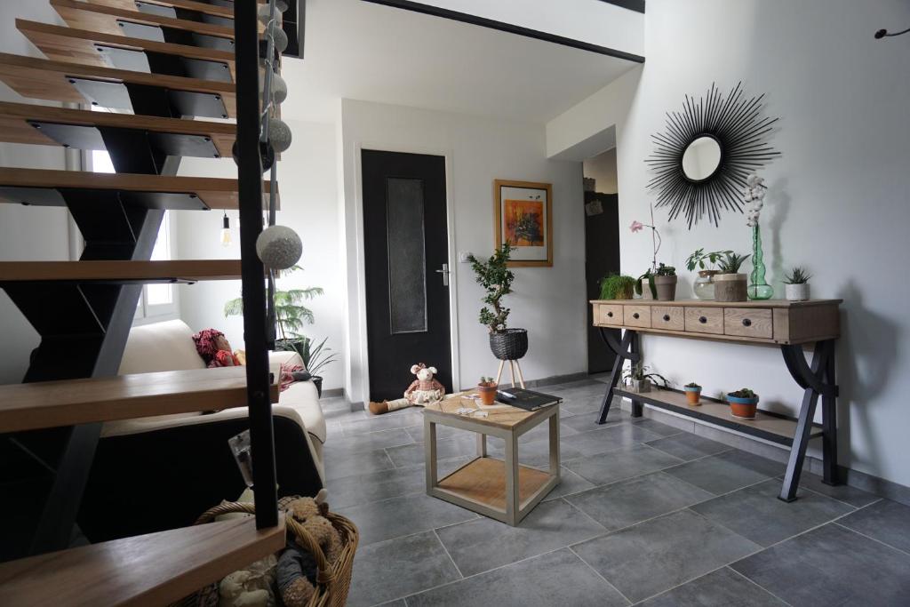 ein Wohnzimmer mit einer Treppe und einem Spiegel in der Unterkunft le Nid Douillet in Chènehutte-les-Tuffeaux