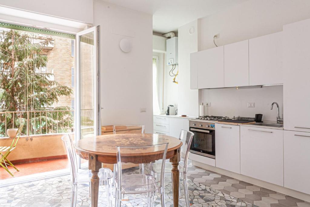 une cuisine avec des placards blancs et une table en bois dans l'établissement BnButler - Casa Lario - Isola District, à Milan