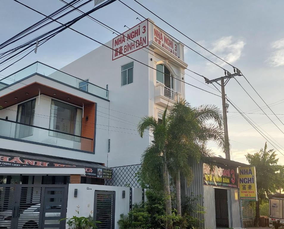 een wit gebouw met een bord aan de zijkant bij NHÀ NGHỈ BÌNH DÂN SỐ 3 in Bạc Liêu