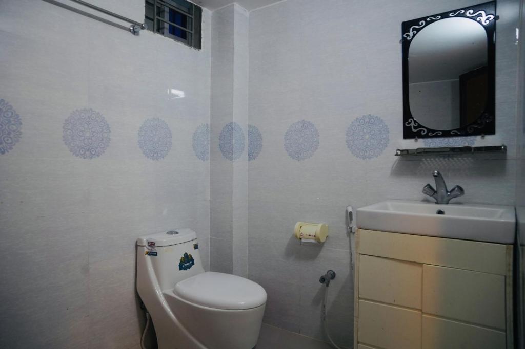 uma casa de banho com um WC, um lavatório e um espelho. em Elite Cox's Resort em Cox's Bazar