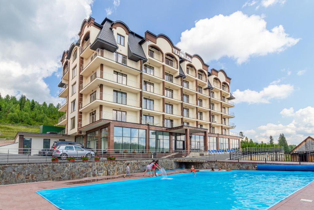 un hôtel avec une piscine en face d'un bâtiment dans l'établissement Elena Spa Resort, à Bukovel