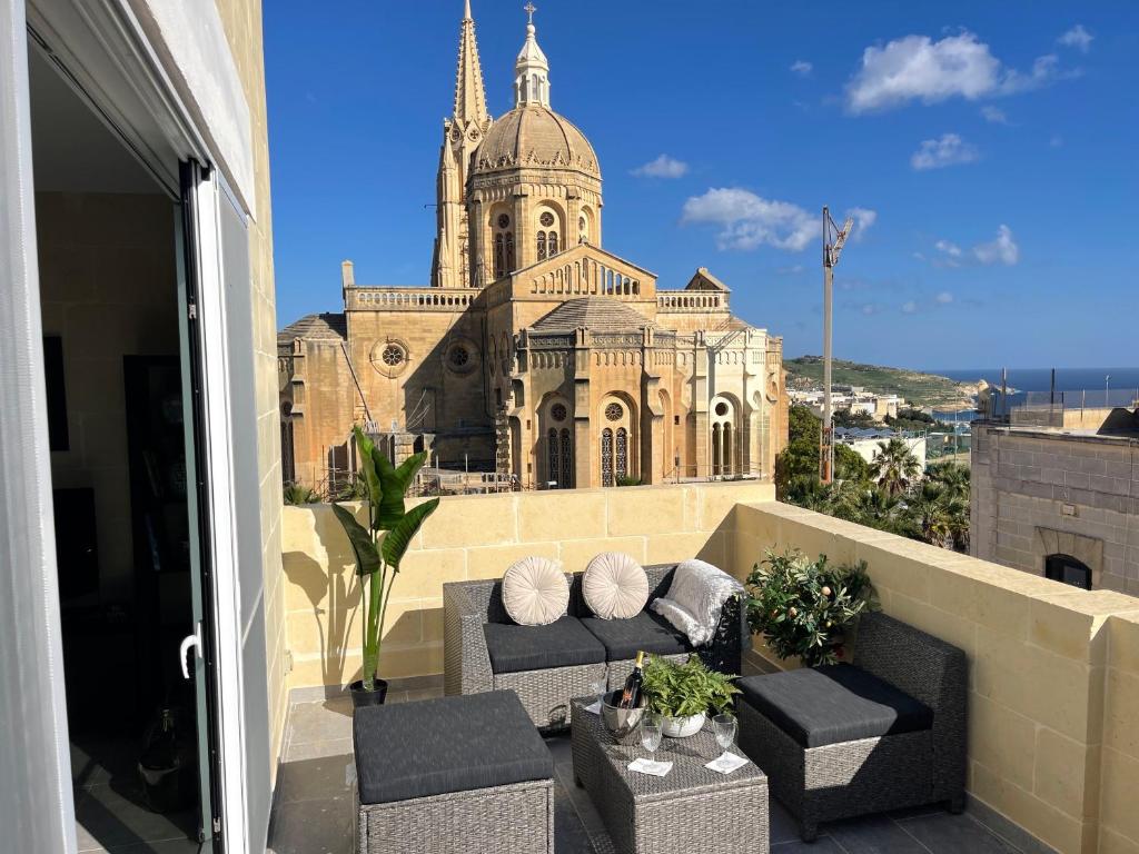 a balcony with couches and a large building at Ta Phyllis - Apartments & Villas with Sunset & Sea Views in Għajnsielem