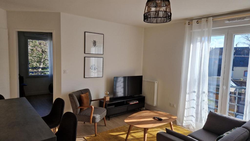 a living room with a tv and a table and chairs at Charmant T2 proche Gare in Laval