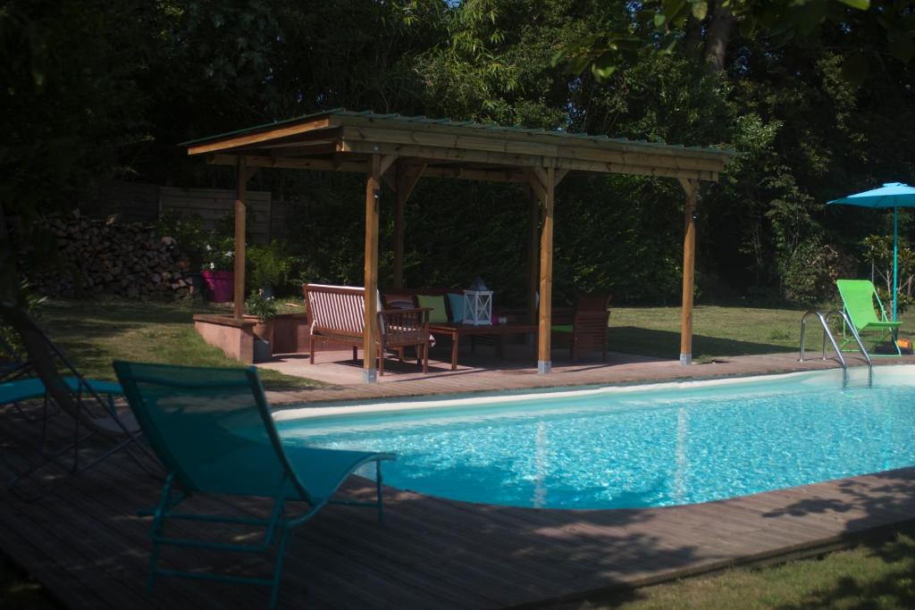 una piscina con cenador, mesa y sillas en Alaudy Vacances Séjours écologiques - 3 gites, en Ossages