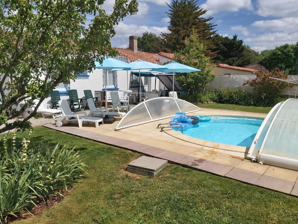 un patio trasero con piscina y sombrilla en Villa Octavière Gîte Rural, en La Chapelle-Achard