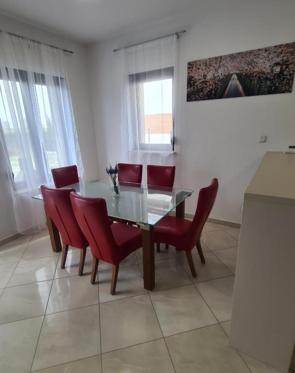 a dining room with a glass table and red chairs at Dom pod Wroclawiem19 in Domasław