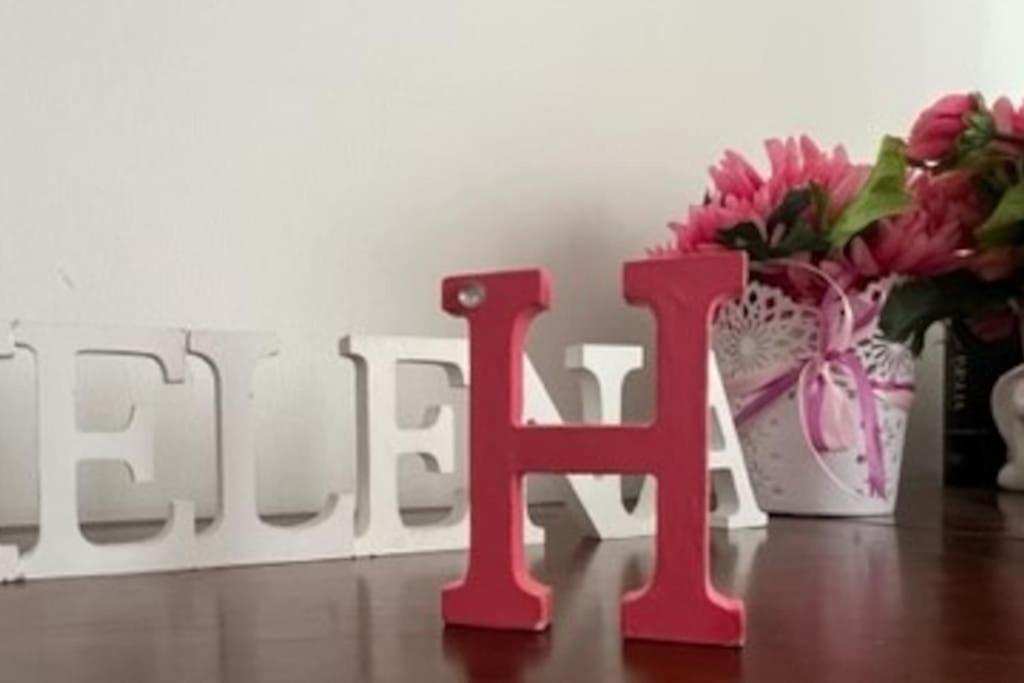 a pink letter h next to a vase of flowers at Helena House in Senhora da Hora