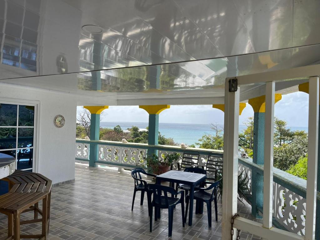 balcón con mesa, sillas y vistas al océano en Posada buena vista al mar en Providencia