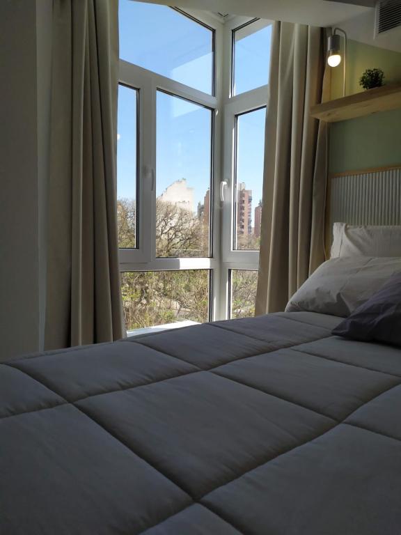 a bed in a room with a large window at Cañada Suites in Córdoba