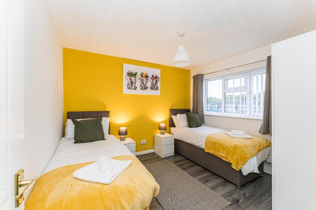 two beds in a room with yellow walls at AMAZING CONTRACTOR HOUSE 3 bedroom warm modern house free secure off road parking, wifi & sky sleep upto 8 guest s in Aintree