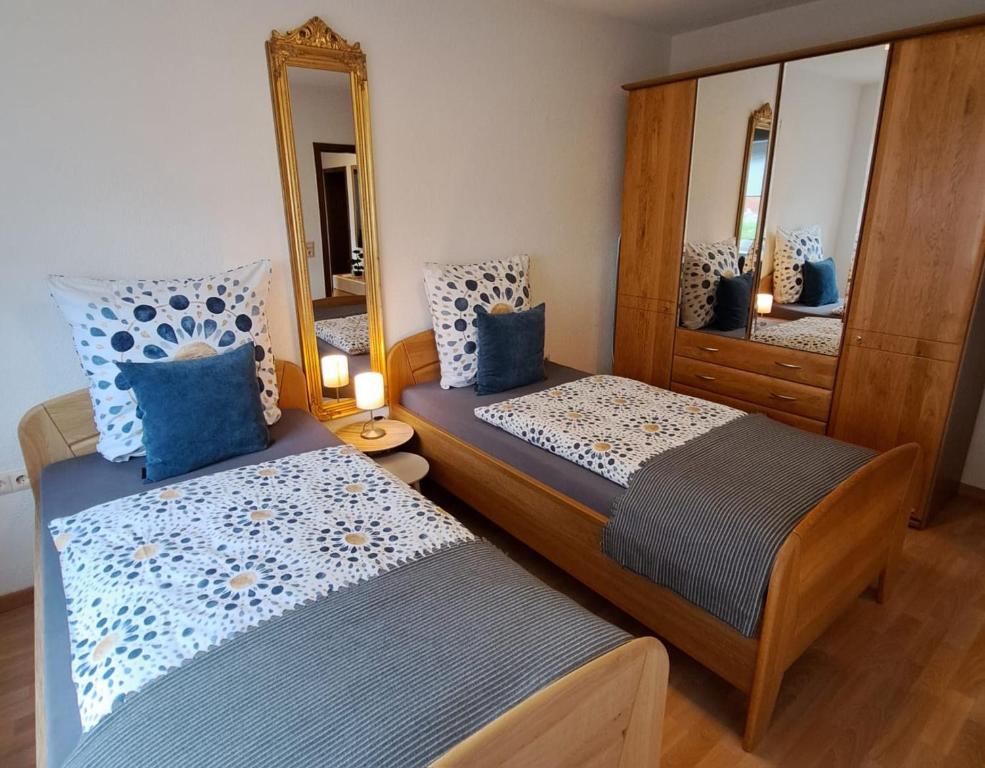 1 dormitorio con 2 camas y espejo en Ferienwohnung Am Reitersgäßchen, en Blankenrath