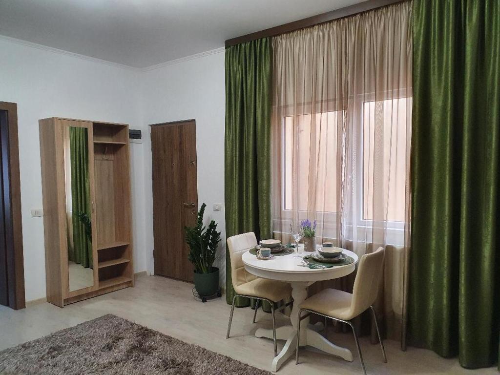 ein Esszimmer mit einem Tisch und einem grünen Vorhang in der Unterkunft Luk's Central Residence in Constanţa