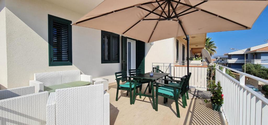 balcone con tavolo, sedie e ombrellone di Casa SantaBarbara a Marina di Ragusa