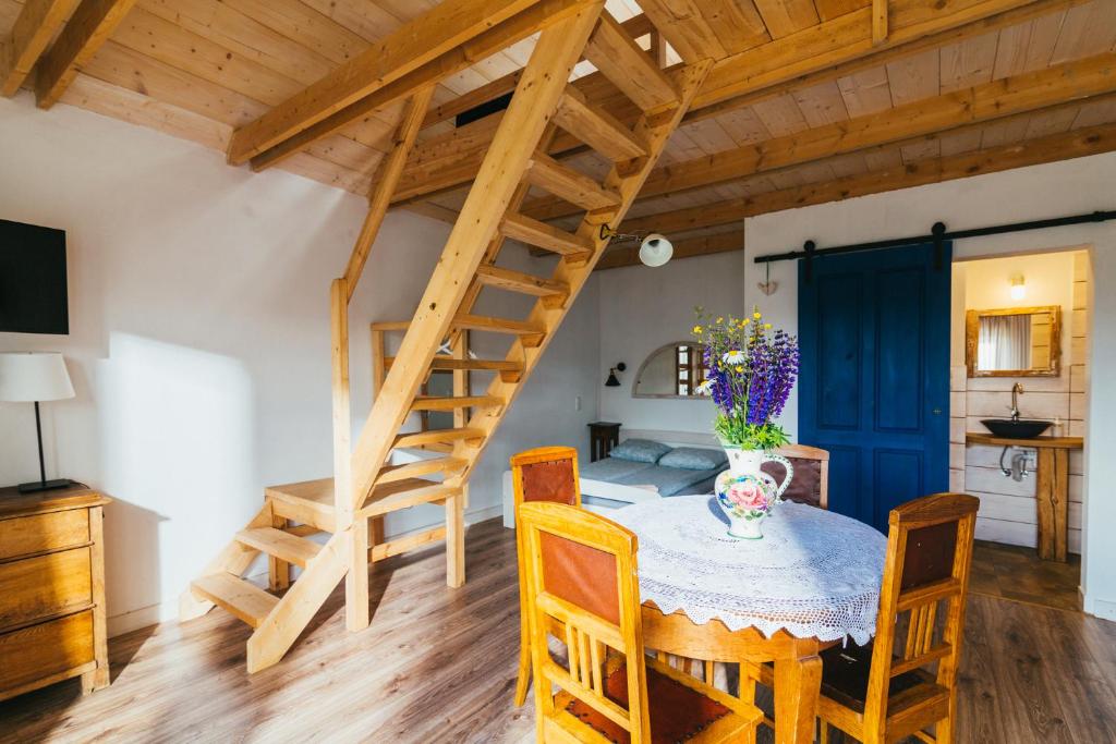 une salle à manger avec une table en bois et un escalier en colimaçon dans l'établissement Apartamenty na Pastwisku, à Szymbark