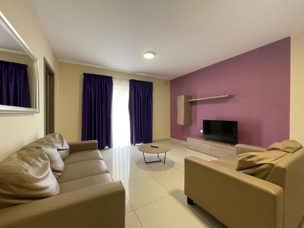 - un salon avec un canapé et une télévision dans l'établissement NSTS Manche Residence, à Il-Gżira