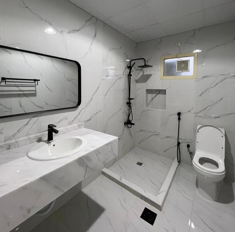 a white bathroom with a sink and a toilet at Algor Farm in Qūr